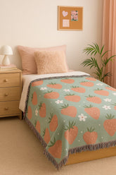 Dorm room setup with strawberry woven blanket on bed