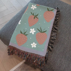 Boho strawberry woven blanket folded on a couch, girly decor