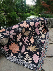 Woven autumn tapestry throw with maple leaves and black backdrop