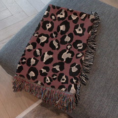Detailed view of burgundy animal print woven throw blanket texture and weave pattern