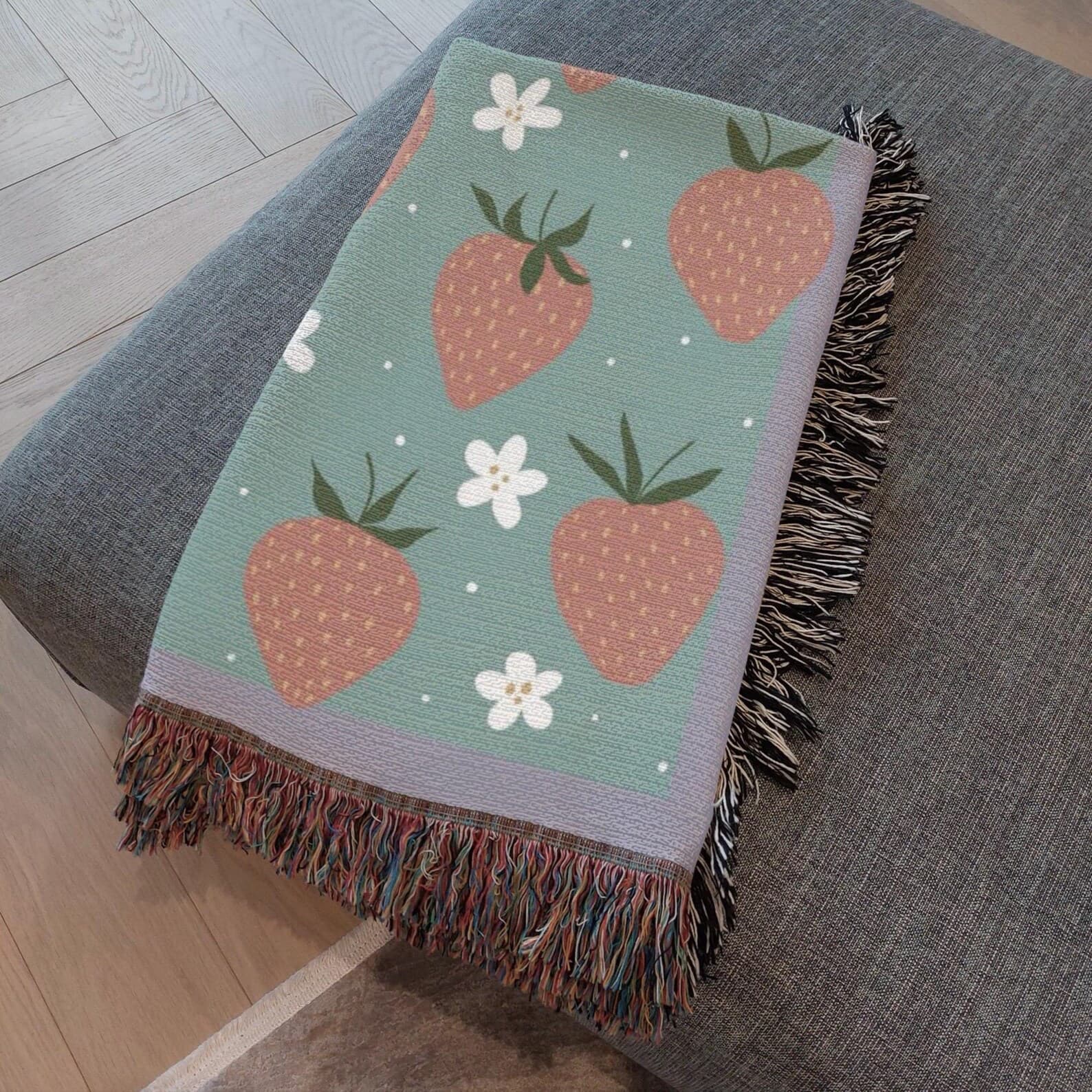Boho strawberry woven blanket folded on a couch, girly decor