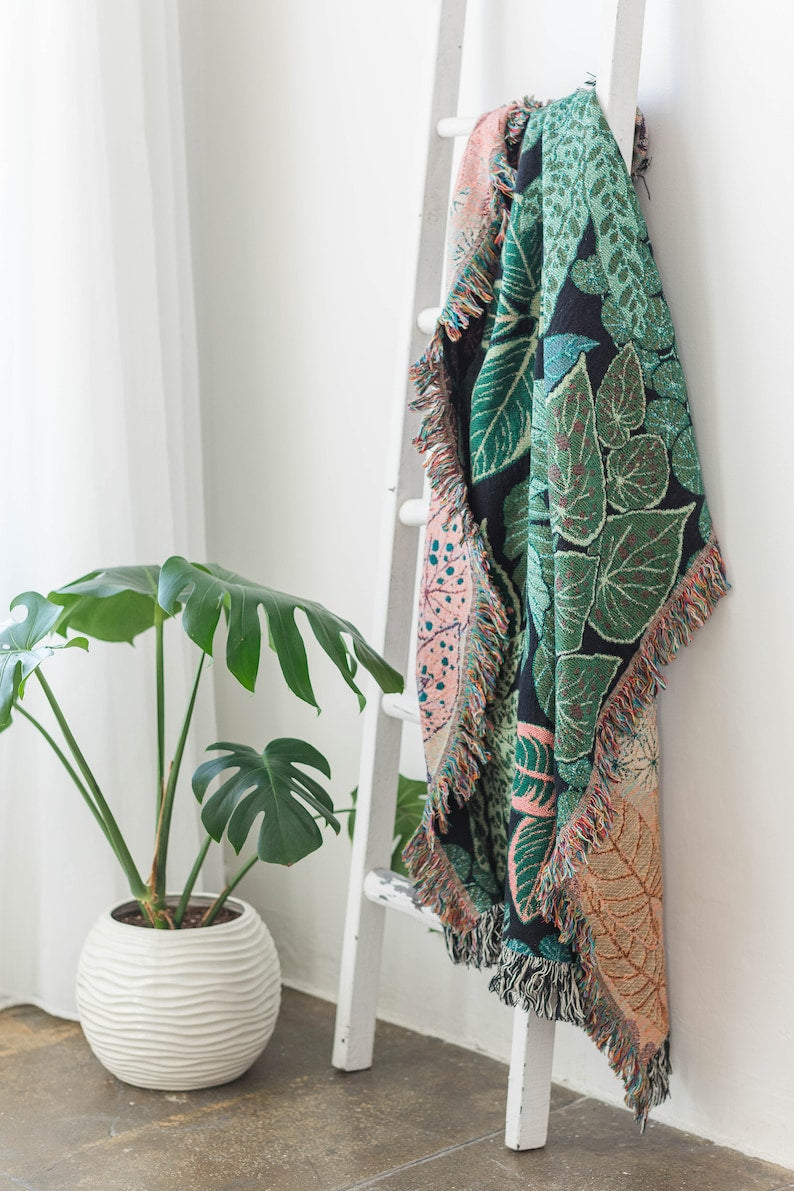 Side angle view of botanical woven blanket showing fabric drape and hanging style
