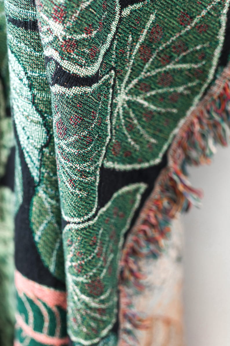 Close-up of botanical woven blanket  tropical leaf tapestry showing detailed botanical pattern and fabric texture

