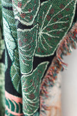Close-up of woven tropical leaf tapestry showing detailed botanical pattern and fabric texture

